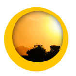 tracteur dans un champ devant un coucher de soleil badge